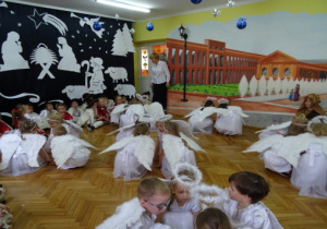 Dzieci przebrane za Anioły kucają w 4 osobowych grupach.